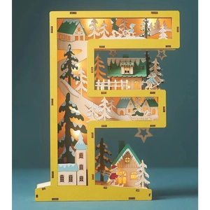 Close-up of wooden letter F LED lamp with 3D winter village scene and warm lights