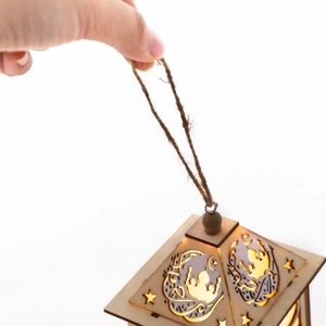 Detail of wooden Ramadan lantern with moon and mosque cutouts glowing in warm light