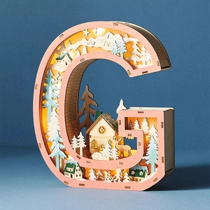 Close-up of wooden letter G LED light with reindeer and forest silhouette cutout