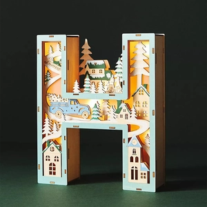 Detail of letter H wooden LED light featuring a 3D winter village scene with snowy trees