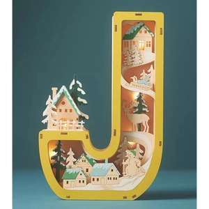 Detail of letter J wooden LED light featuring a winter snow scene with reindeer and trees
