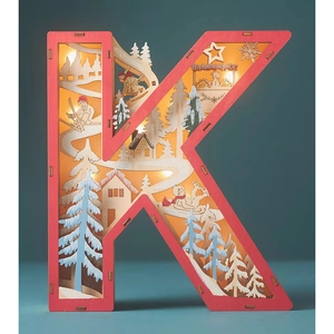 Macro view of wooden letter K Christmas scene with LED lights and winter forest