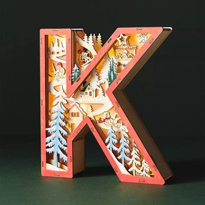 Detail of wooden letter K Christmas light with multi-layer carved winter scene