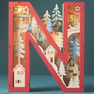 Detail of wooden letter N LED lamp with layered winter scenery and red frame decor