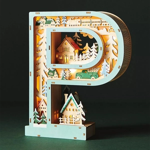 Detail of wooden letter P LED box with laser-cut winter village and warm lighting