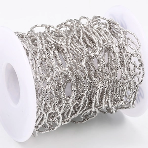 Close-up of diamond-cut stainless steel link chain on white spool for jewelry DIY
