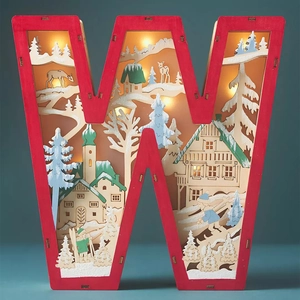 Macro shot of wooden letter W light with laser-cut snowy cabin and reindeer scene