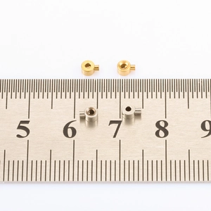 Macro detail of 5mm-6mm gold and silver stainless steel crimp beads on a scale ruler