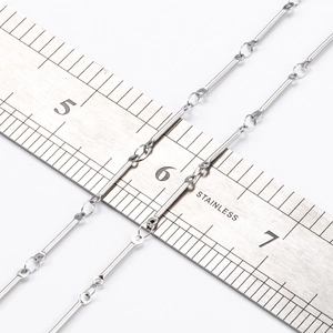 Close-up of silver stainless steel bar link chain next to a ruler for size scale