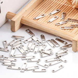 Bulk rectangular stainless steel jewelry tags with laser engraving holes on a wooden surface