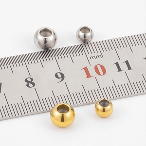 Macro view of gold and silver stainless steel slider beads next to a measuring ruler