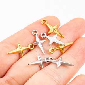 Close-up of small gold and silver stainless steel star charms held in a hand for scale