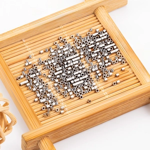 Polished silver stainless steel crimp beads for jewelry making displayed in a bamboo tray