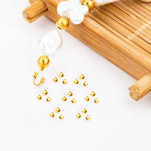 Golden stainless steel crimp beads for jewelry making with pearl bracelet on bamboo tray