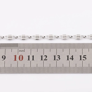 Close-up of stainless steel chain links with mesh texture next to a metric ruler