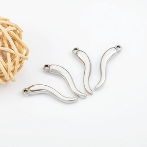 Gros plan de quatre pendentifs cornicello en acier poli pour la création de bijoux