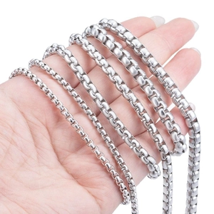 Various widths of polished stainless steel box chains for necklaces held by a hand