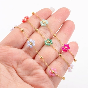 Golden stainless steel chain with colorful beaded flowers held in hand against white