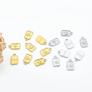 Macro view of rectangular stainless steel charms with butterfly relief and Beauty engraving