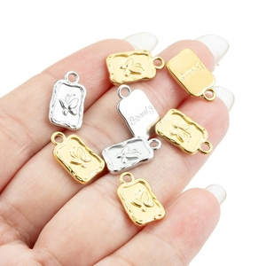 18k gold and silver stainless steel butterfly rectangle pendants held in hand