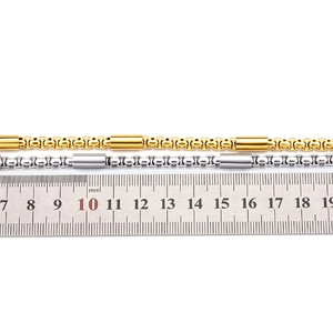 Dettaglio di catene cilindriche in acciaio inox 18k oro e argento con righello graduato