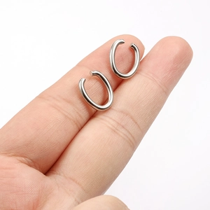 Paia di ear cuff ovali in acciaio inossidabile lucido mostrati su un dito per scala