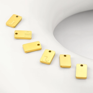 Close-up of polished gold rectangular letter charms with engraved alphabet details