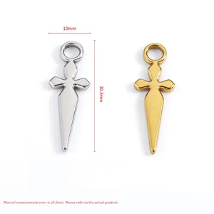 Macro shot of 18k gold and silver sword-shaped cross pendants showing precise dimensions