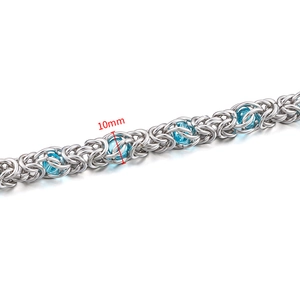 Macro detail of 10mm stainless steel Byzantine chain with blue beads and intricate weaving