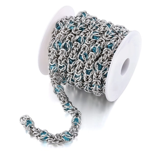 Macro shot of stainless steel dragon bone chain with blue glass beads on white spool