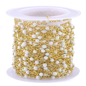 Gold stainless steel cross chain with white enamel beads on a plastic spool for jewelry making