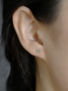 Detail view of square gold earrings with turquoise stones on ear for size reference