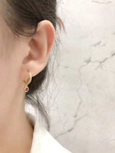 Gros plan sur des boucles d'oreilles créoles avec cristaux blancs et rubis rouge rond