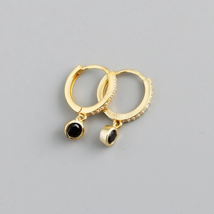 Vue macro de boucles d'oreilles créoles dorées avec zircons et pendentifs en pierre noire