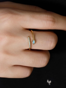 Macro shot of gold adjustable ring with light blue marquise stone and pavé accents
