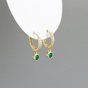 Détail de boucles d'oreilles créoles en argent 925 plaqué or avec gemmes vertes