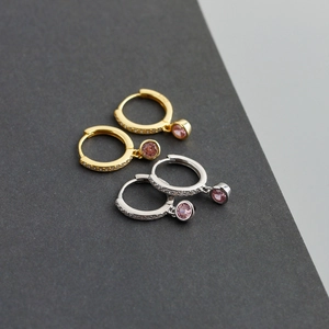 Gros plan de créoles argent et or avec pierres roses et sertissage pavé brillant