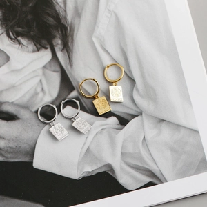 Detalle de pendientes de aro en oro y plata con la Torre Eiffel en una revista retro