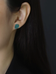 Close-up of a melting smiley face earring with green enamel drip on a model ear