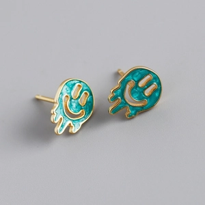 Macro shot of molten-style smiley earrings with gold edges and green enamel details