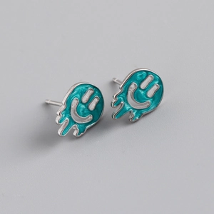 Macro detail of silver S925 smiley face earrings with melting turquoise enamel effect