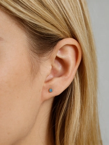 Close-up of a square sky blue zircon earring with a gold bezel set on a model ear