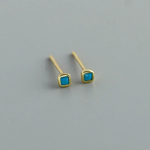 Detail of square gold stud earrings featuring vibrant turquoise stones in a minimalist design