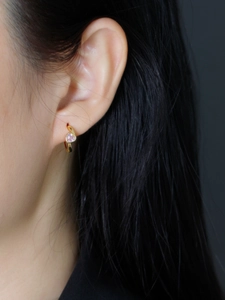 Gros plan d'une boucle d'oreille cœur en zircon rose doré portée sur l'oreille