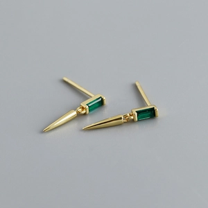 Vue macro des boucles d'oreilles zircon vert émeraude avec pendentif conique doré