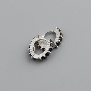 Détail de boucles d'oreilles créoles en argent s925 avec zircons noirs sur fond gris clair