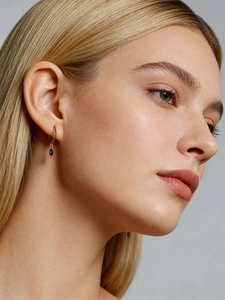 Close-up of gold S925 silver hoop earrings with black stones and a teardrop pendant
