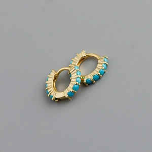 Détail de boucles d'oreilles créoles dorées avec perles turquoise de style bohème épuré