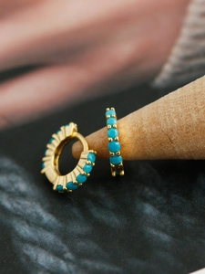 Vue macro de boucles d'oreilles créoles dorées avec pierres bleu turquoise et fermoir