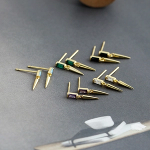 Détail de boucles d'oreilles en argent avec zircon carré et pendentifs à pointe dorée